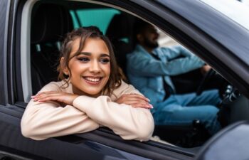 Enjoying travel. Beautiful young couple sitting on the front passenger seats and smiling while handsome man driving a car
