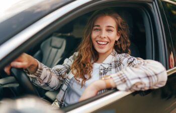 Happy smiling woman inside a car driving in the street